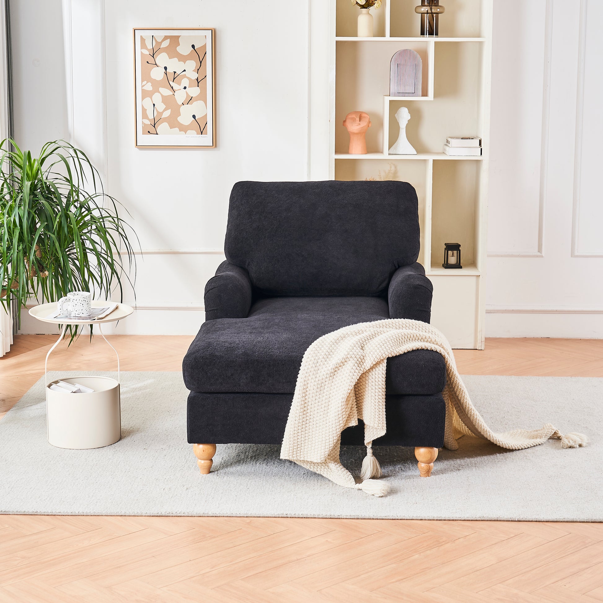 Plush dark gray chaise lounge with natural wood legs and a cream throw blanket