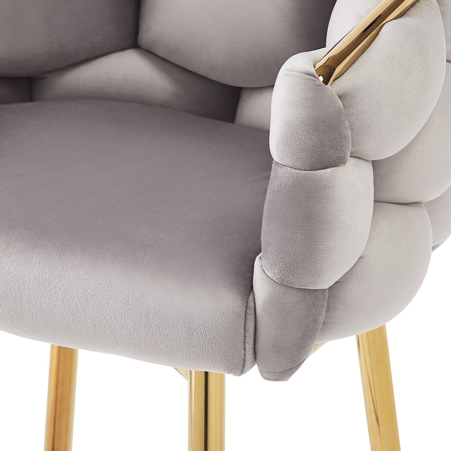 Closeup of a grey velvet chair armrest with plush cushioning and a gold metal accent