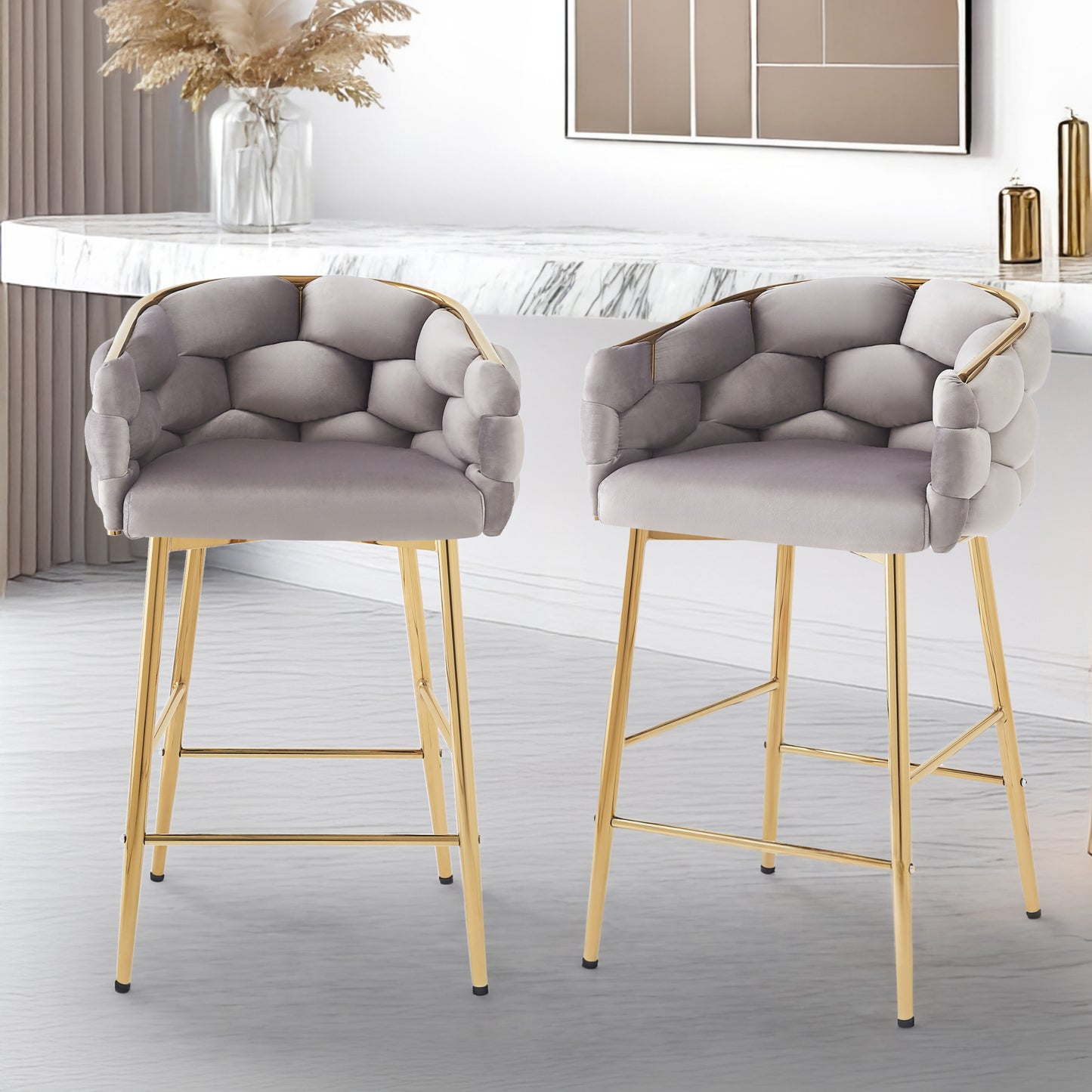 Two grey velvet bar stools with tufted geometric seats and gold metal legs in a modern kitchen setting