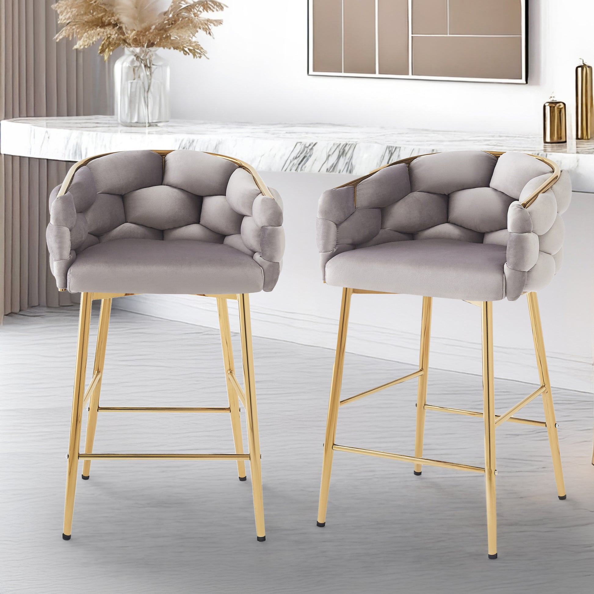 Two grey velvet bar stools with tufted geometric seats and gold metal legs in a modern kitchen setting