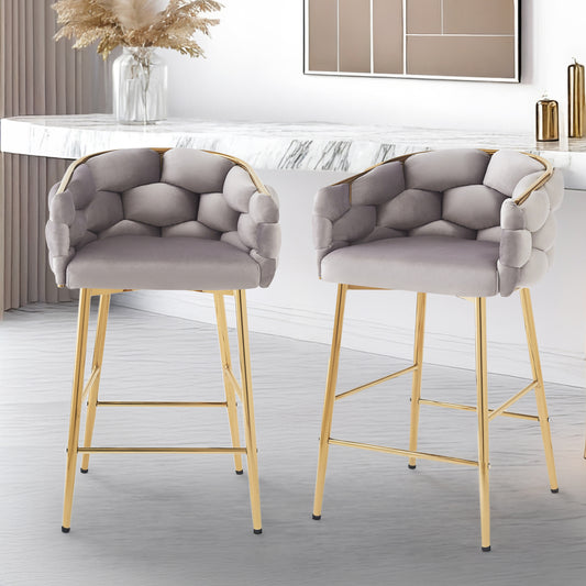 Two grey velvet bar stools with tufted geometric seats and gold metal legs in a modern kitchen setting