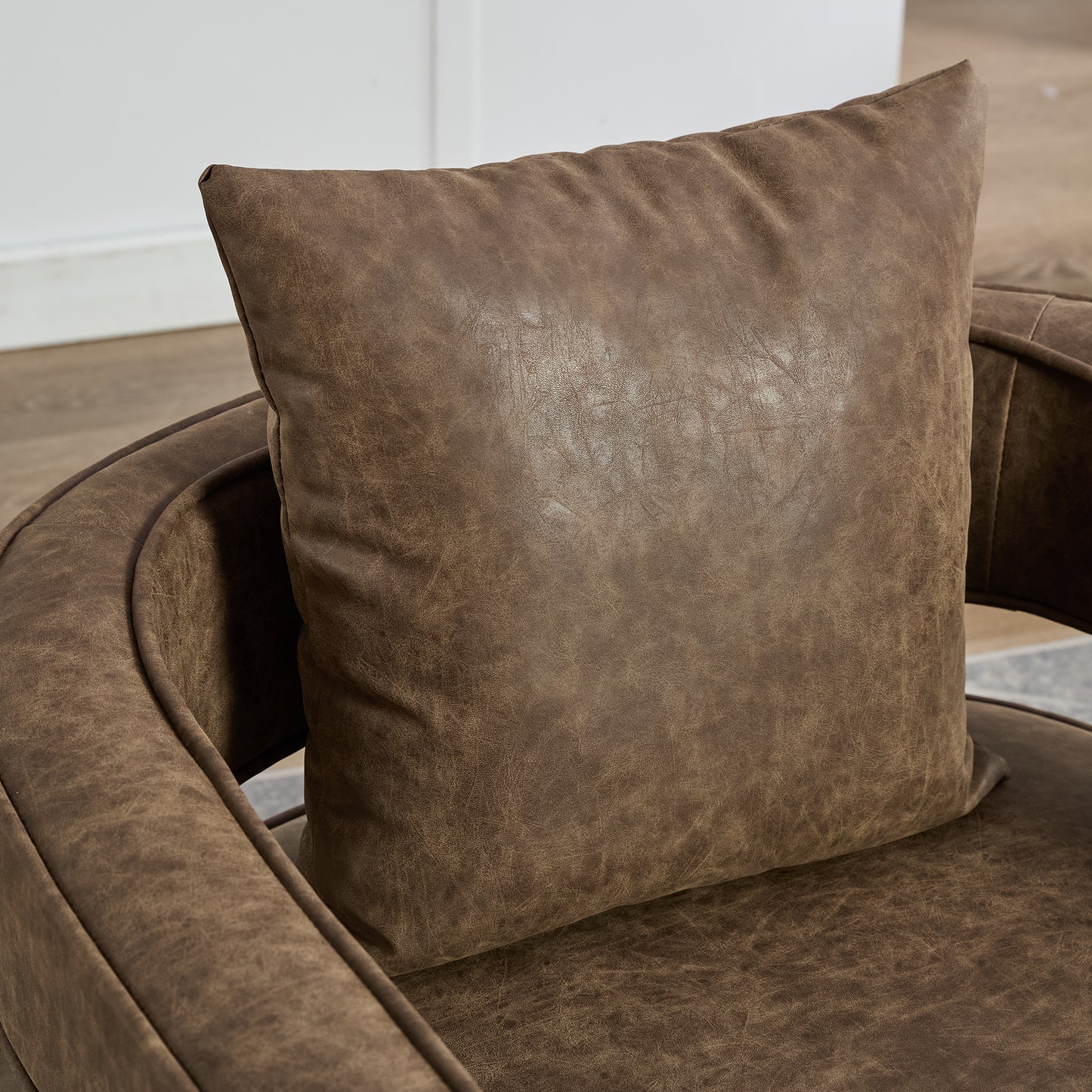 Brown distressed faux leather accent pillow on a matching armchair