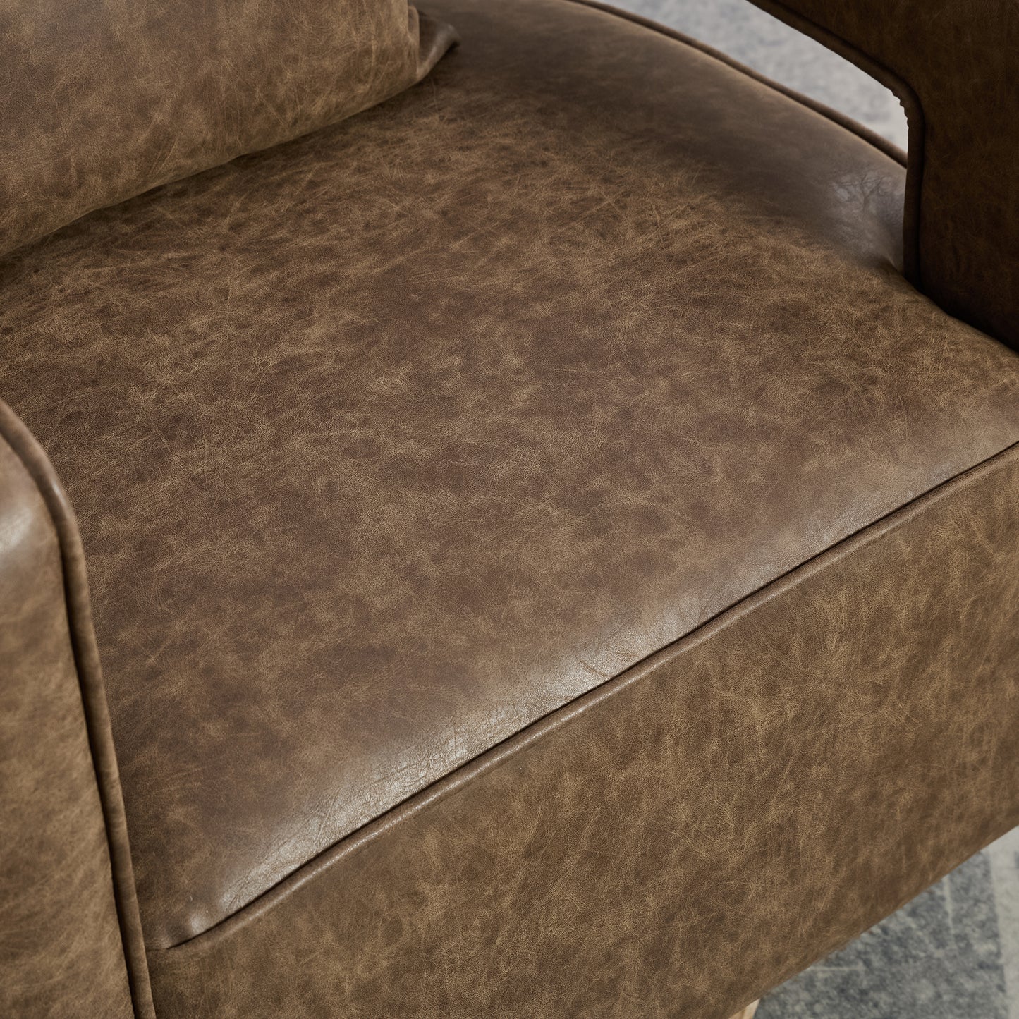 Closeup of distressed brown faux leather armchair seat