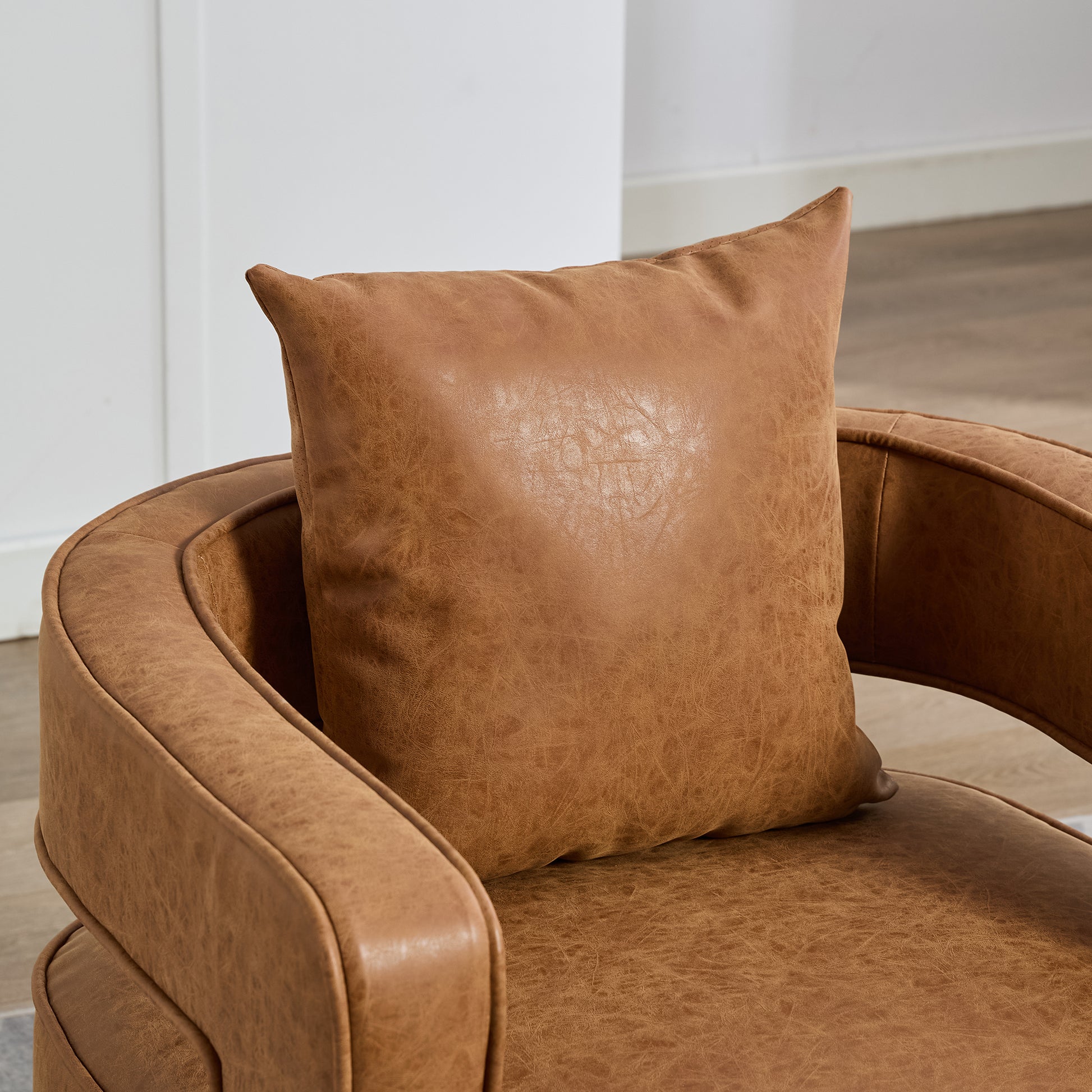 Tan distressed leather accent pillow on a tan leather armchair