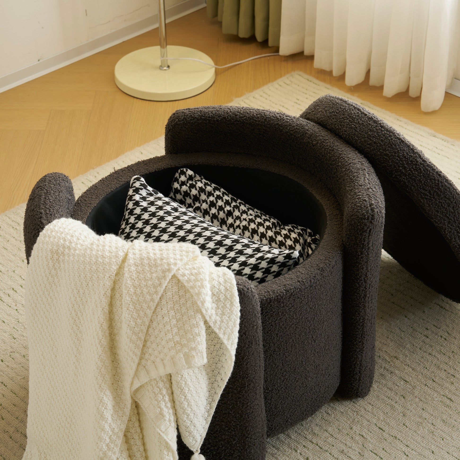 Plush dark gray storage ottoman with houndstooth and cream knit pillows