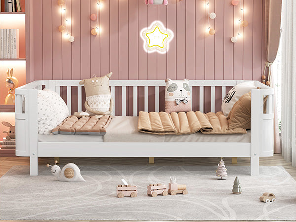 White wooden toddler bed with plush animal pillows and quilted mattress pads