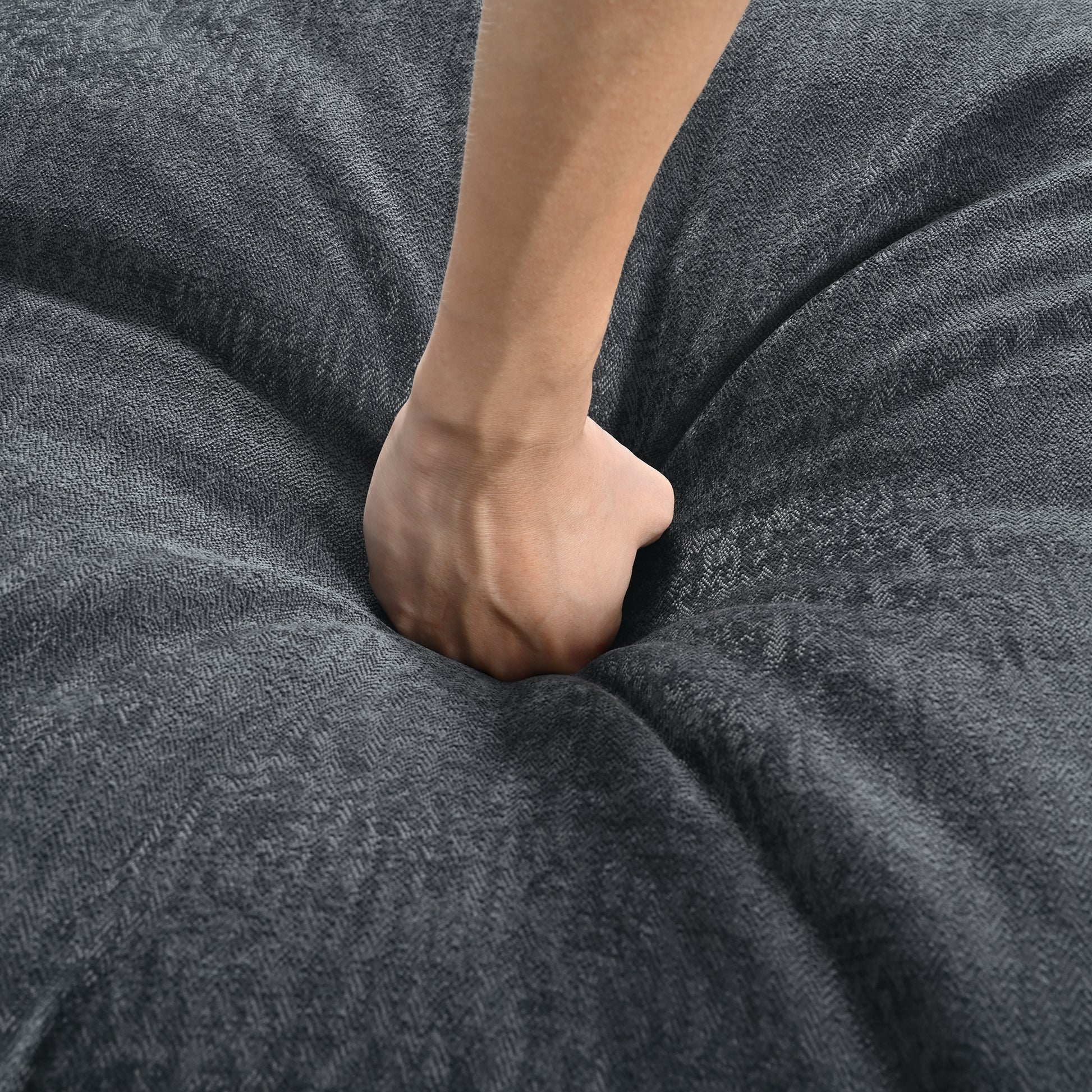 Hand pressing into soft grey fabric showing textured weave