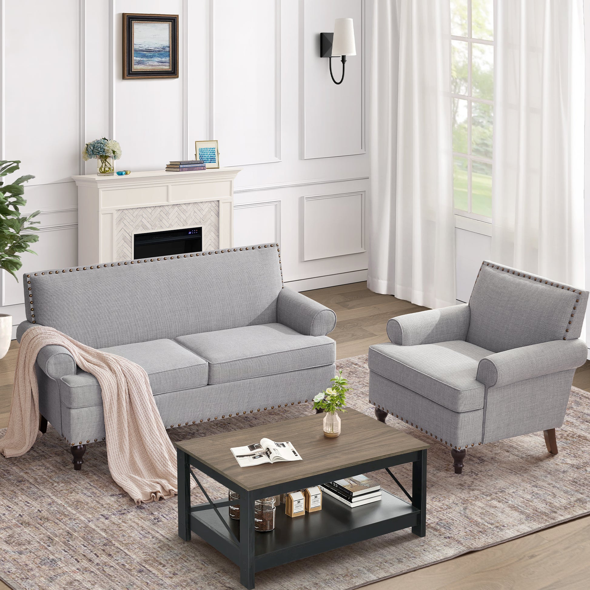 Grey upholstered sofa with decorative nailhead trim and a light pink throw blanket