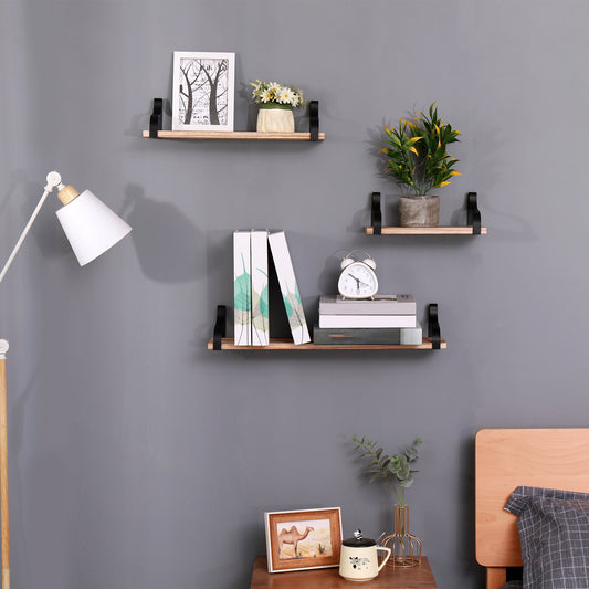 Natural wood floating shelf with black brackets displaying framed art and daisies