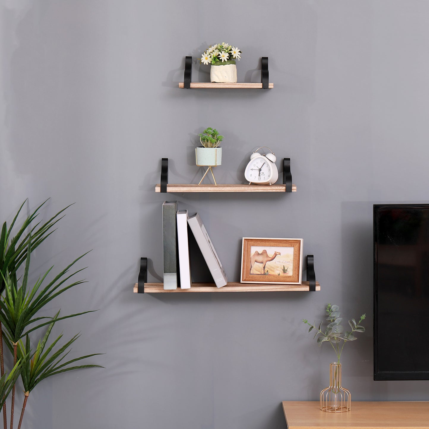 Wooden floating shelf with black brackets holding white daisy bouquet