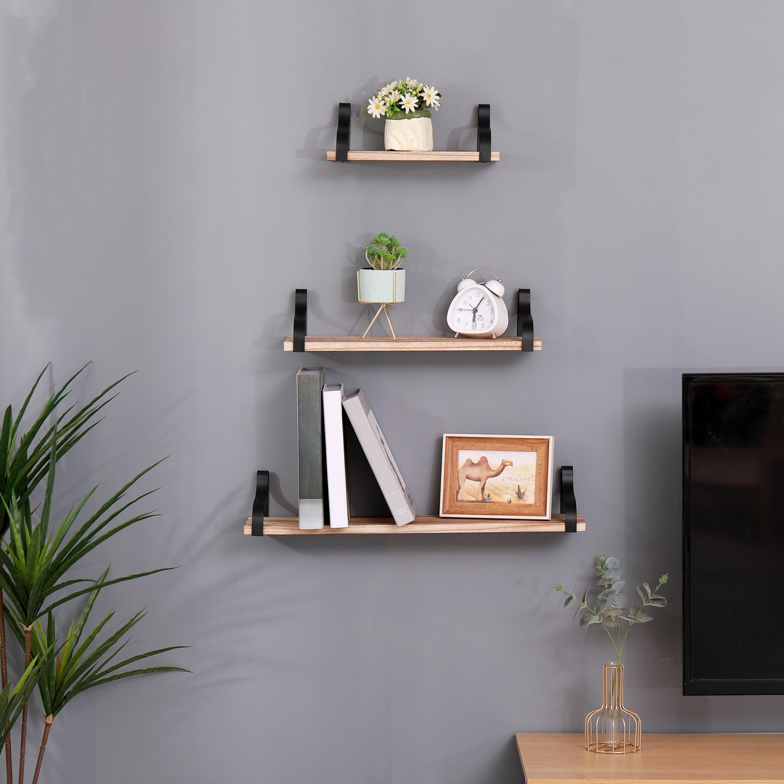 Wooden floating shelf with black brackets holding white daisy bouquet