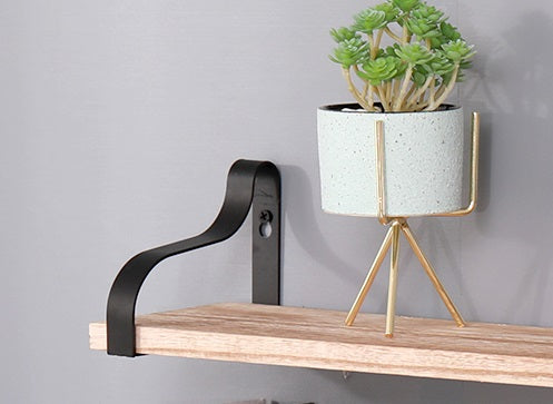 Minimalist white speckled planter with gold tripod stand on wooden shelf
