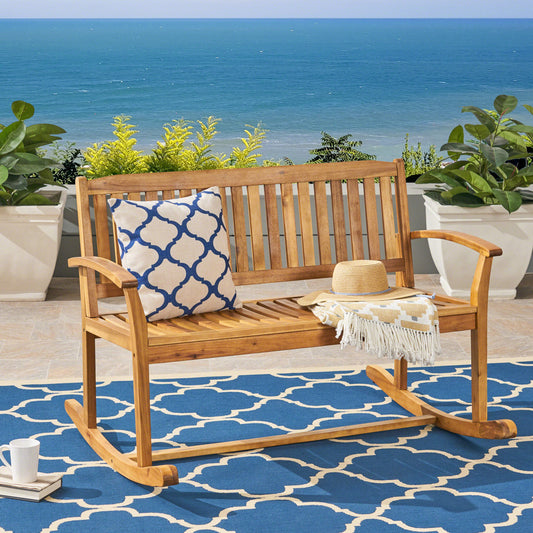 Wooden patio rocking bench with blue patterned cushion and straw hat