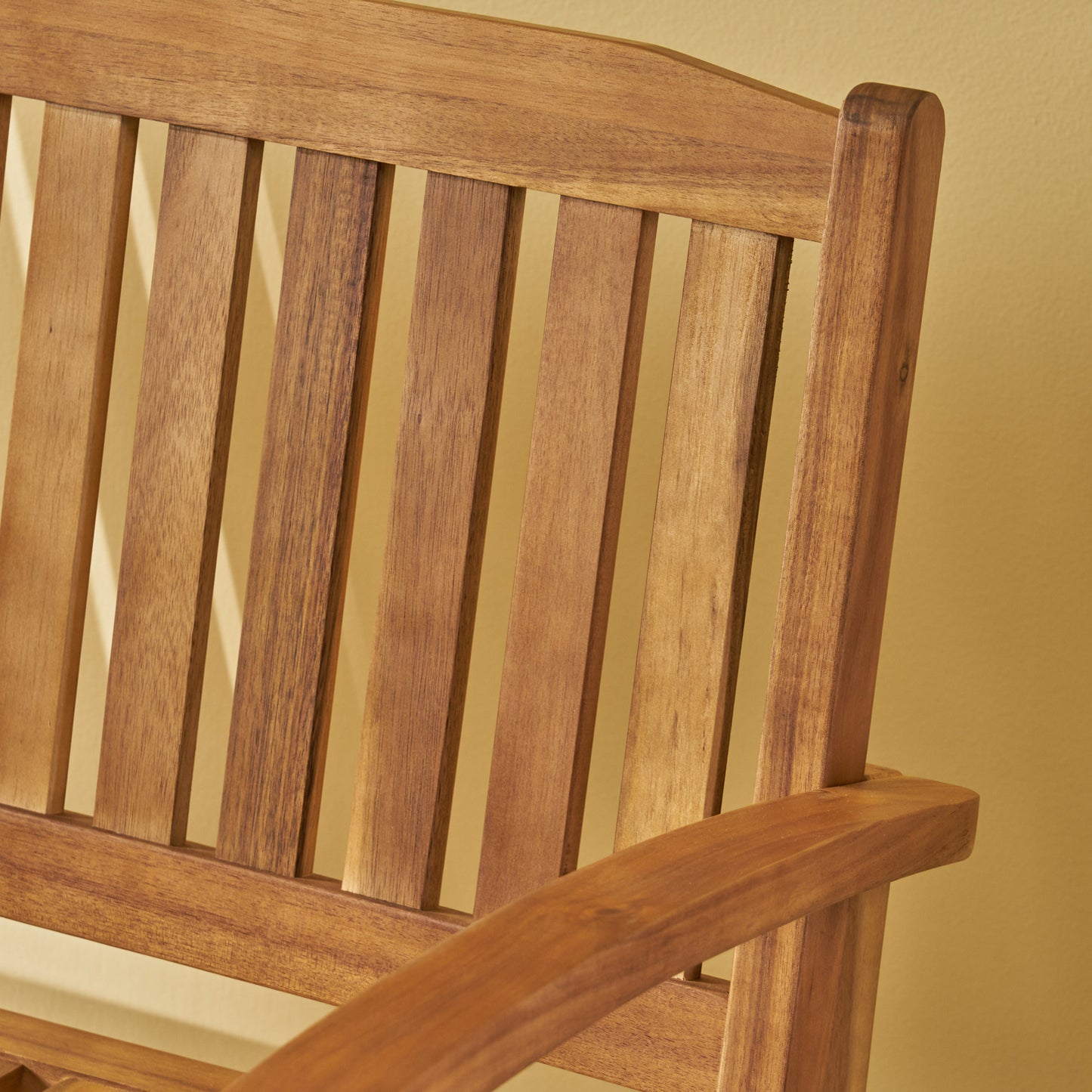 Closeup of a warm brown wooden slatted garden bench backrest and armrest