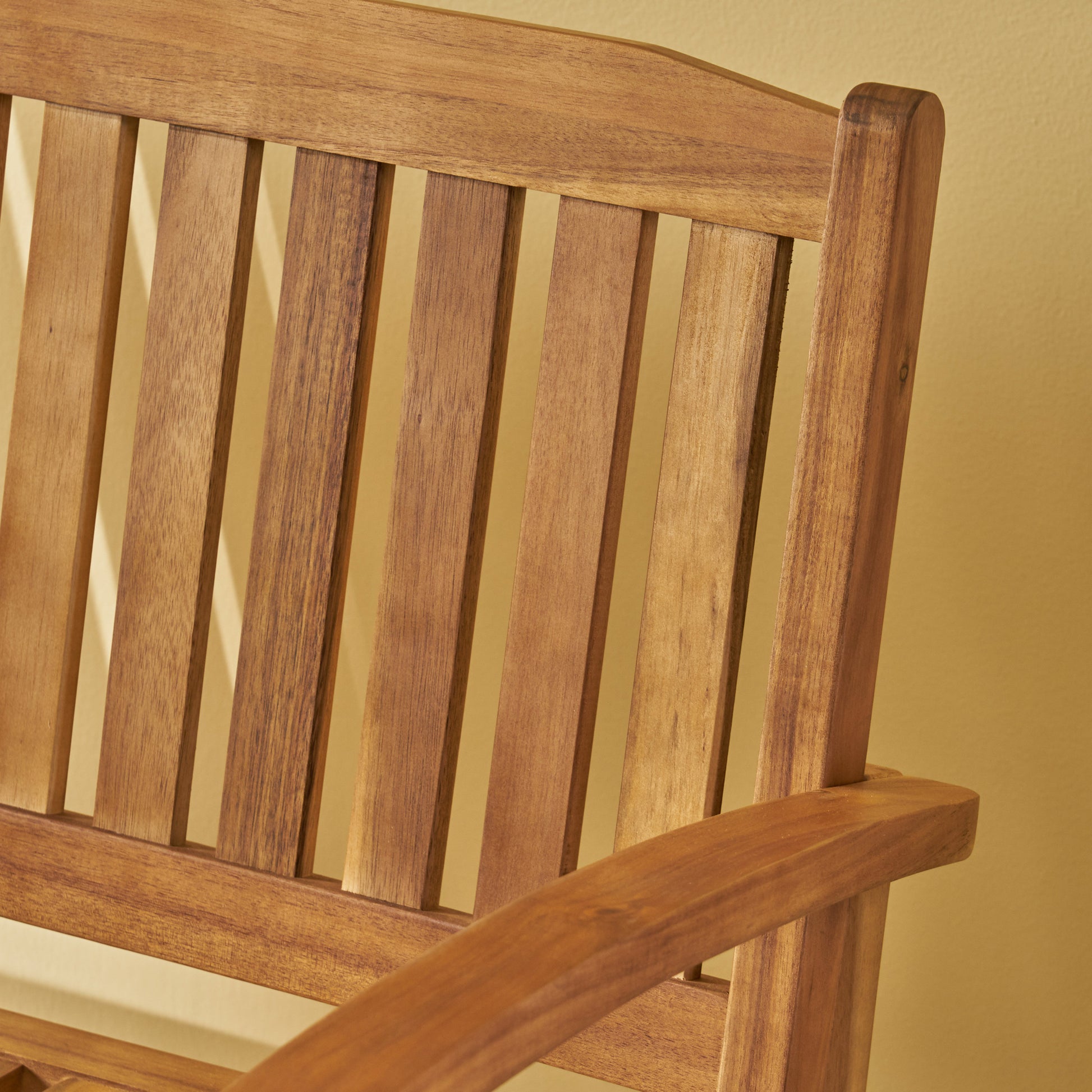 Closeup of a warm brown wooden slatted garden bench backrest and armrest