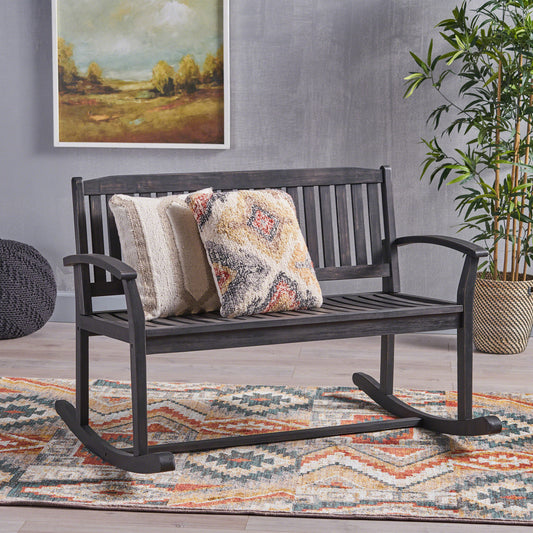 Dark gray wooden outdoor rocking bench with two patterned throw pillows