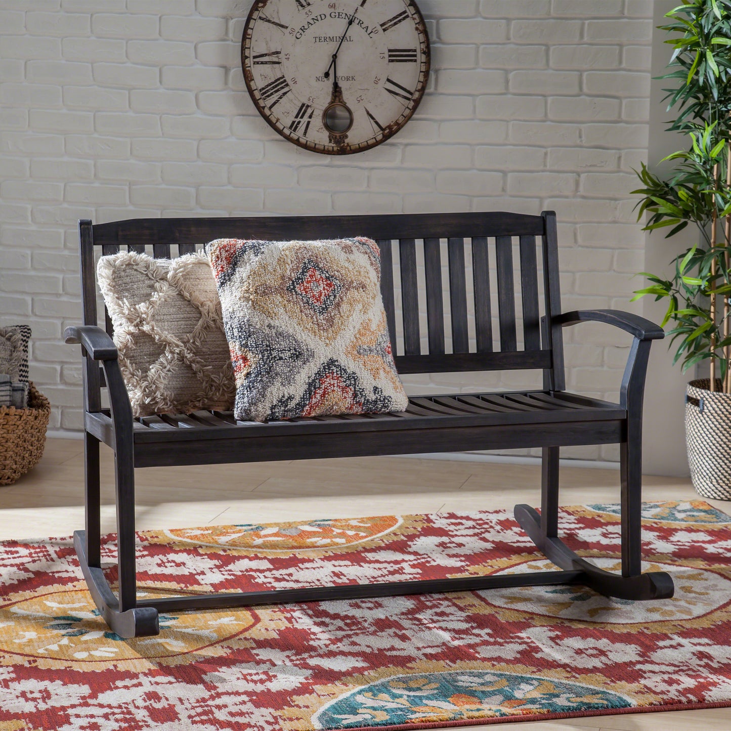 Dark wood rocking patio bench with decorative pillows