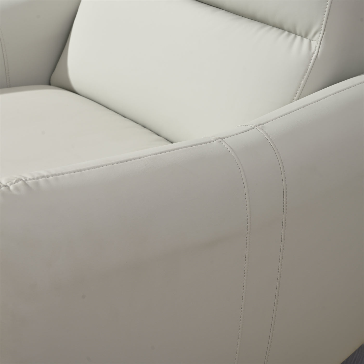 Closeup of a plush light gray faux leather armchair with visible stitching details