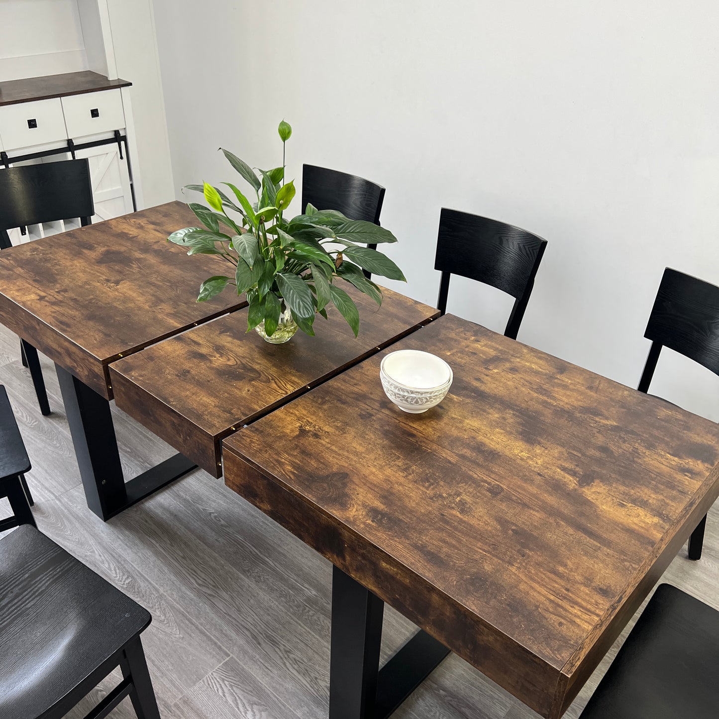 Rustic brown wood dining table with black metal legs and four black chairs