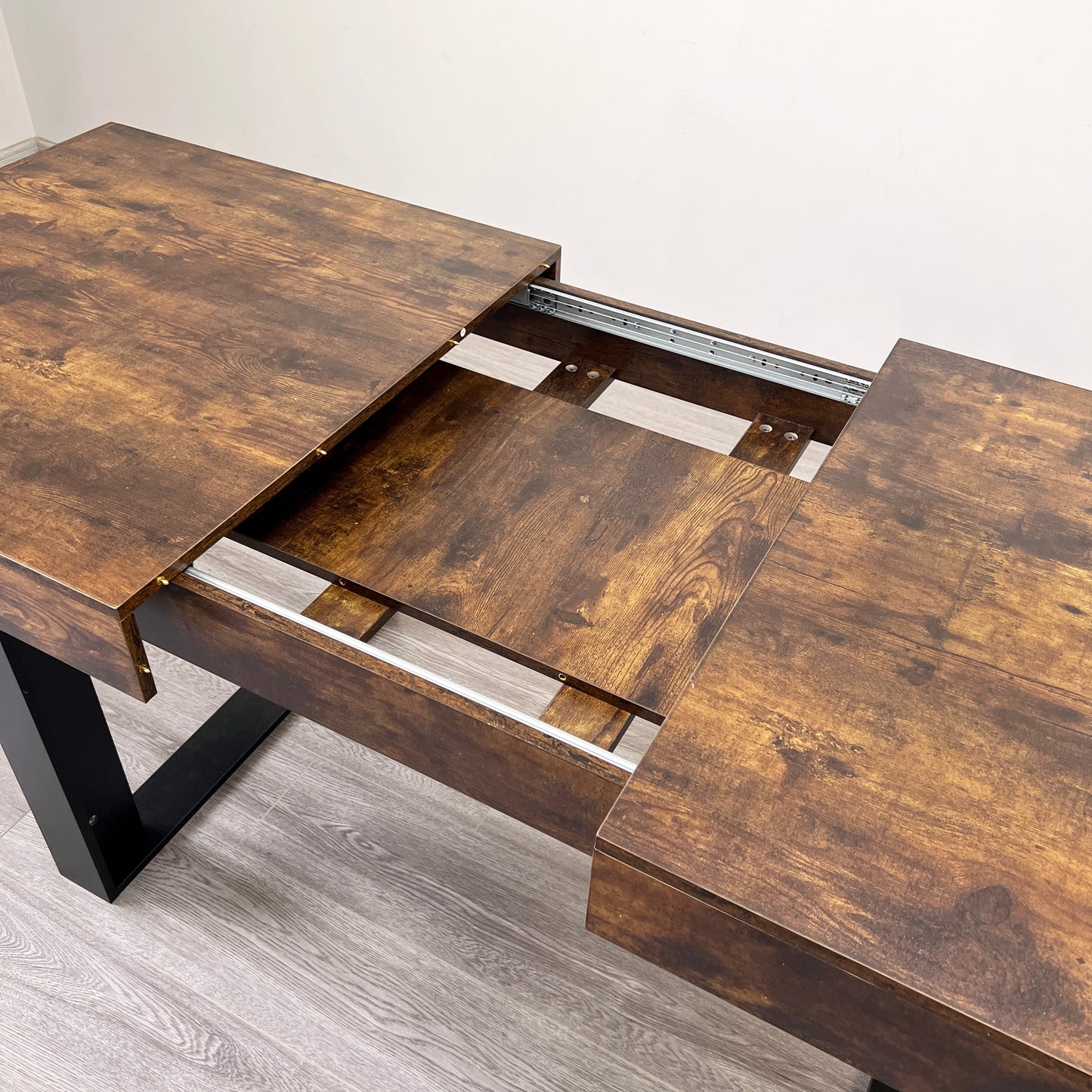 Rustic brown extendable dining table with dark metal legs and visible drawer slides