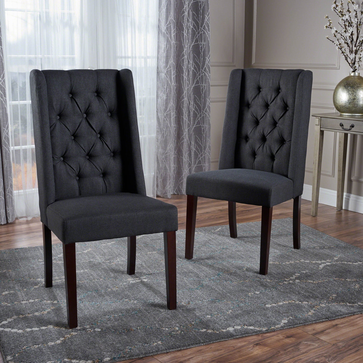 Dark gray upholstered dining chairs with tufted backs and dark wood legs