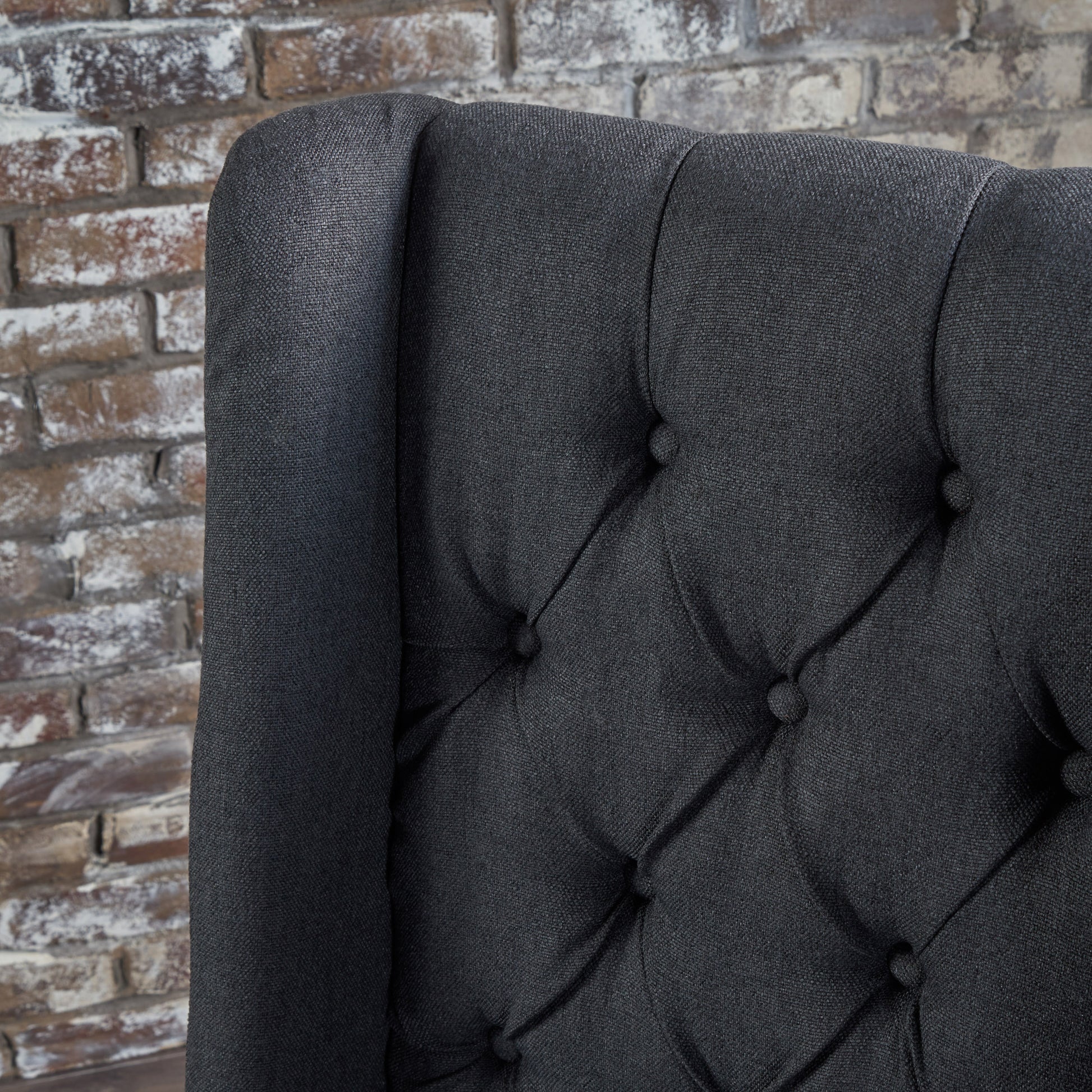 Dark gray tufted armchair detail with textured fabric