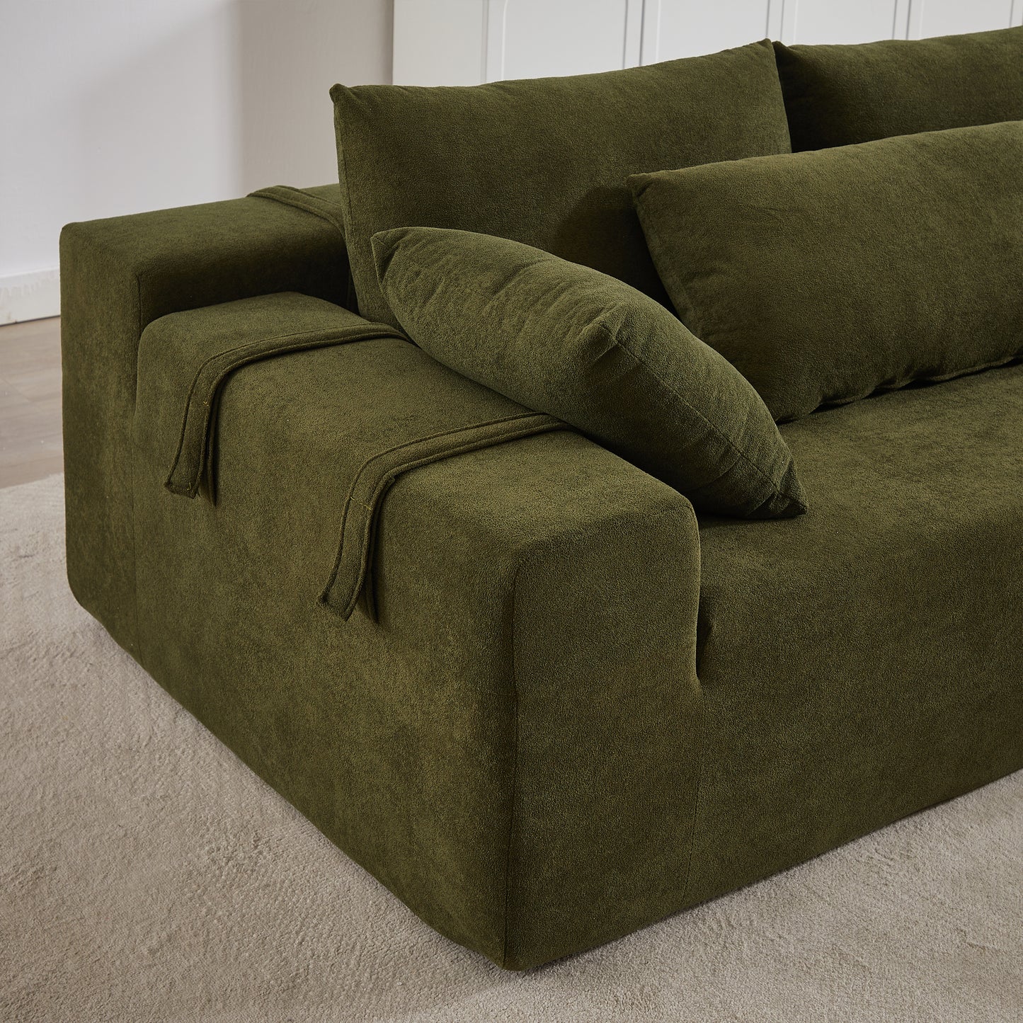 Deep green velvet sectional sofa with plush cushions and armrest detail