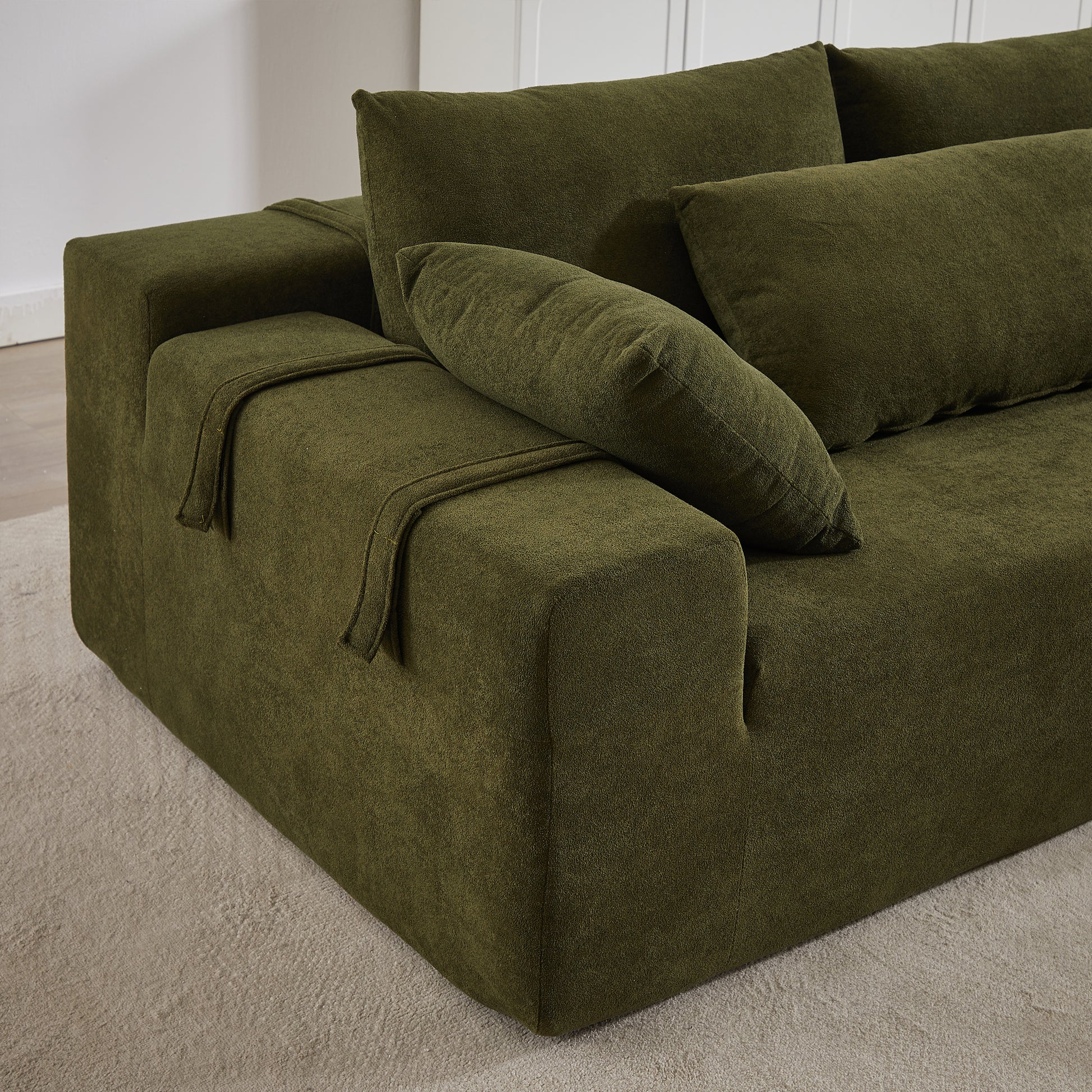 Deep green velvet sectional sofa with plush cushions and armrest detail