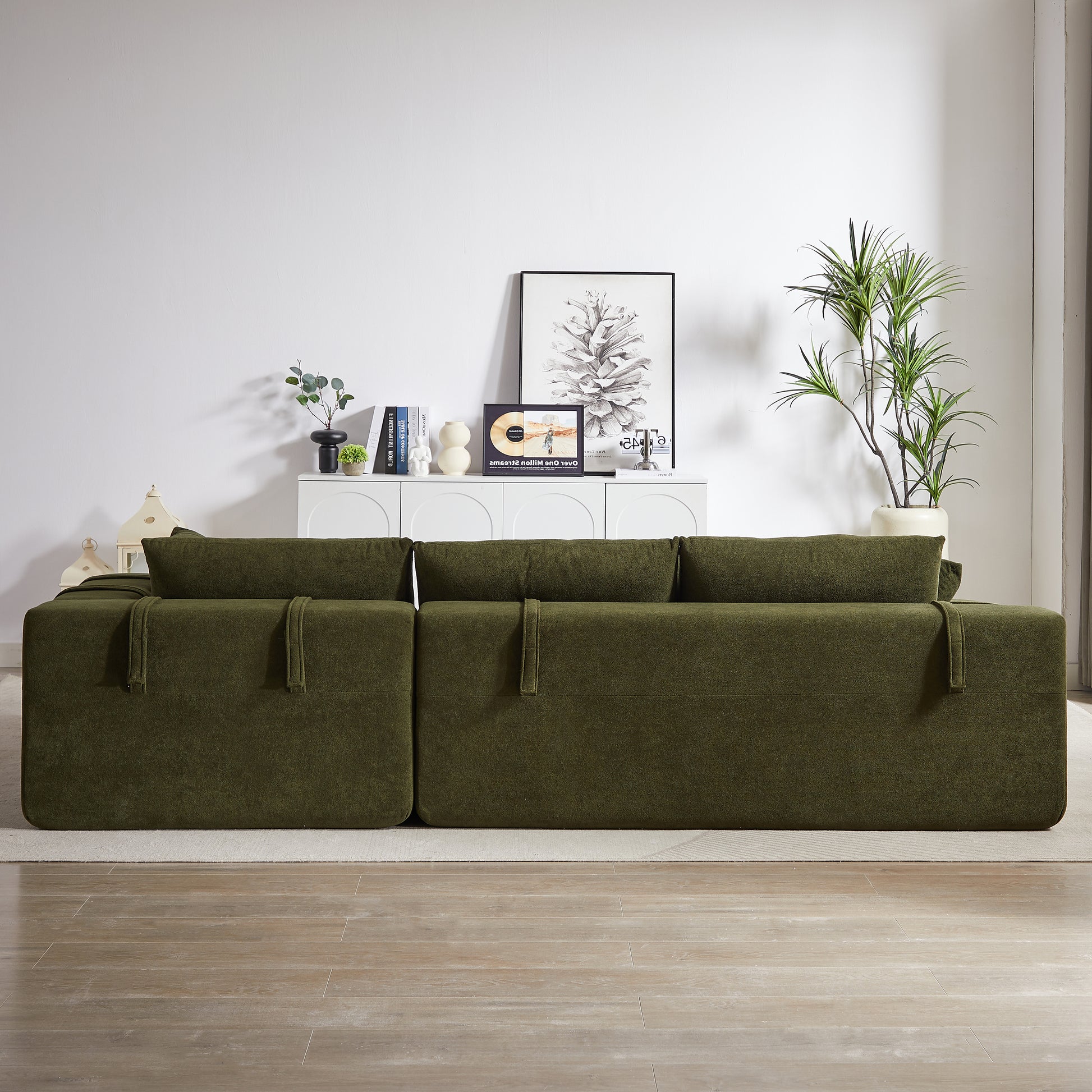Deep green modular sectional sofa with plush cushions and fabric straps