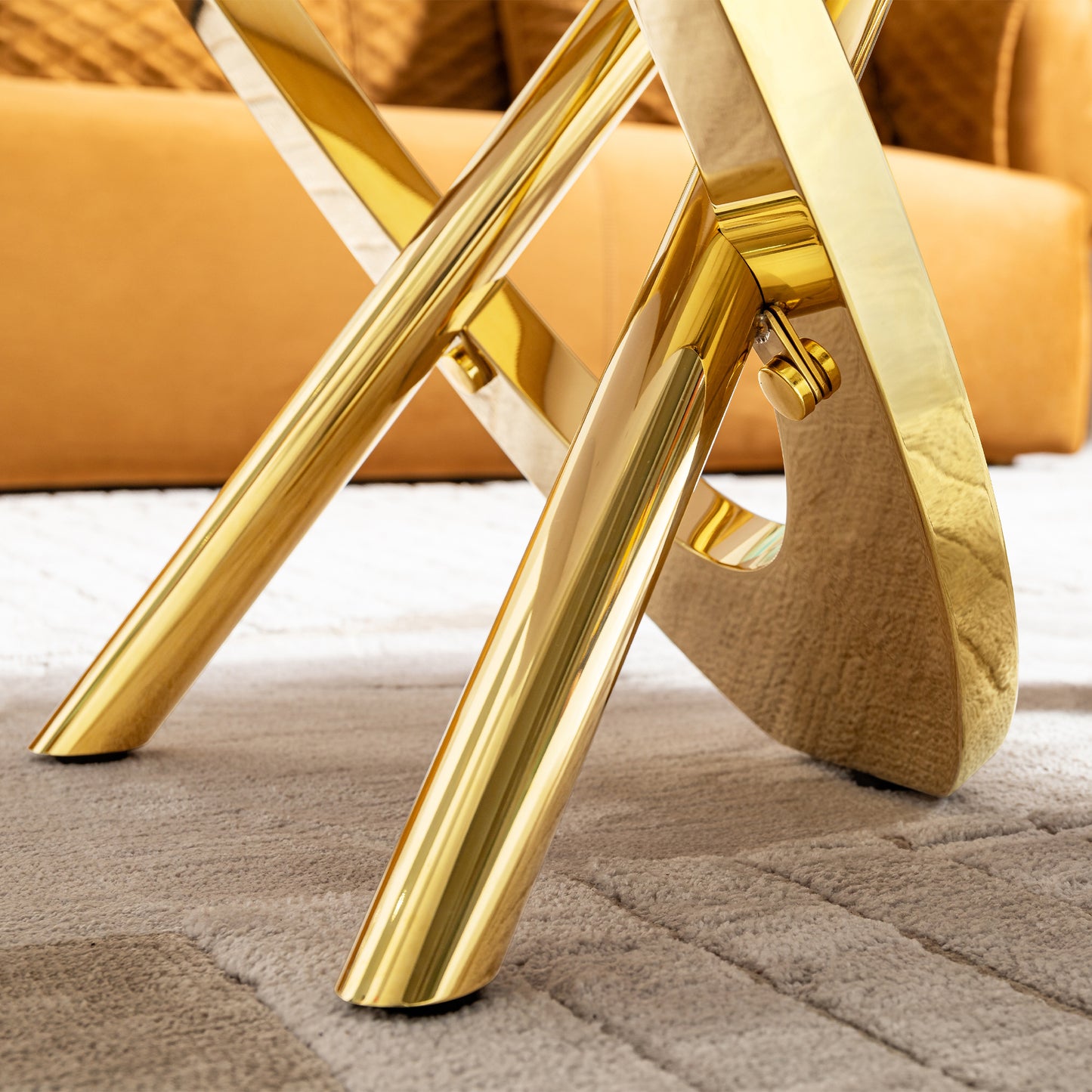 Polished brass Xframe accent chair legs on a textured rug