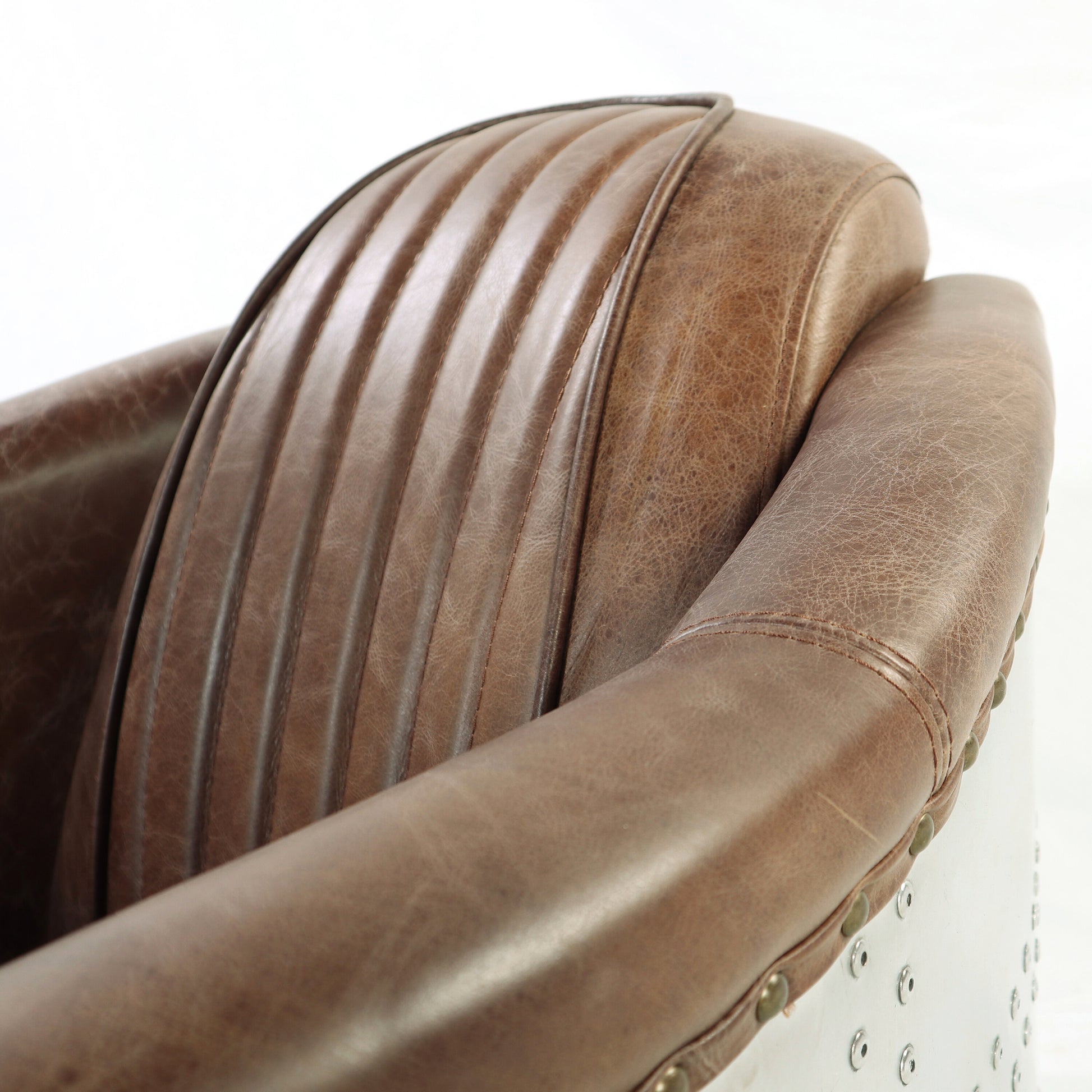 Brown distressed leather aviator armchair seat with vertical stitching detail and metal accents