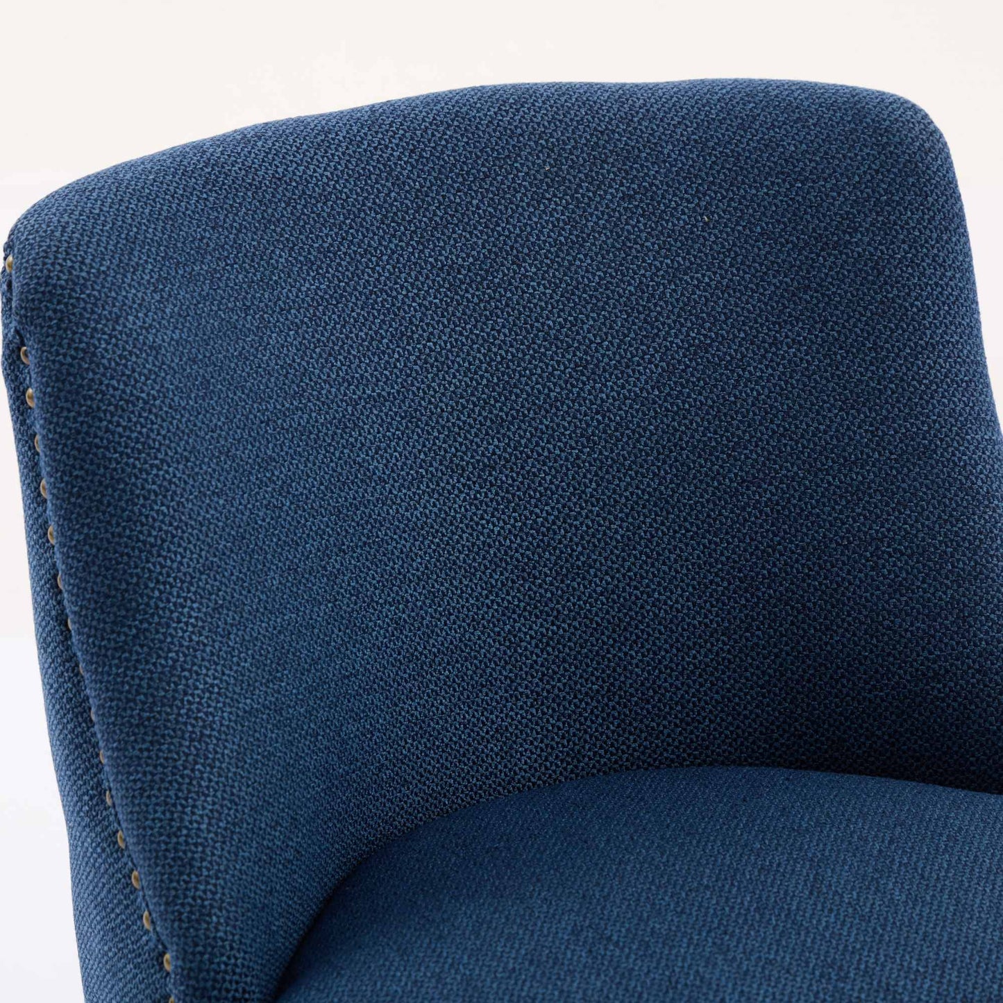 Closeup of textured navy blue fabric on a modern armchair with brass nailhead trim