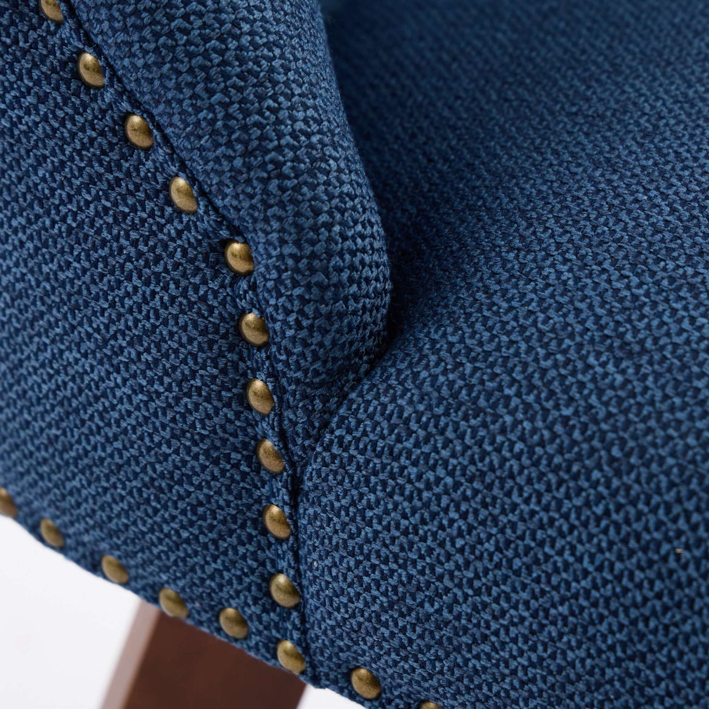 Closeup of navy blue textured fabric on a chair with antique brass nailhead trim