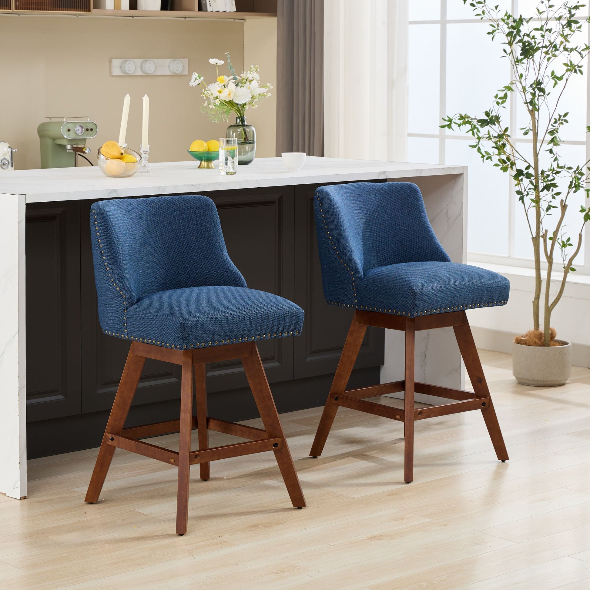 Two navy blue upholstered bar stools with nailhead trim and wooden legs perfect for kitchen island seating
