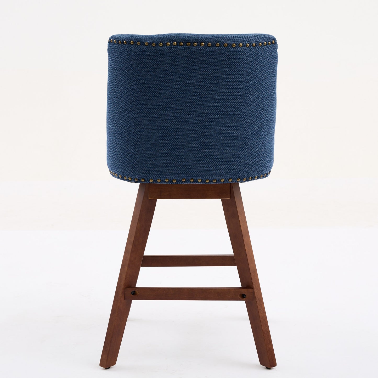 Back view of a navy blue upholstered bar stool with bronze nailhead trim and wooden legs