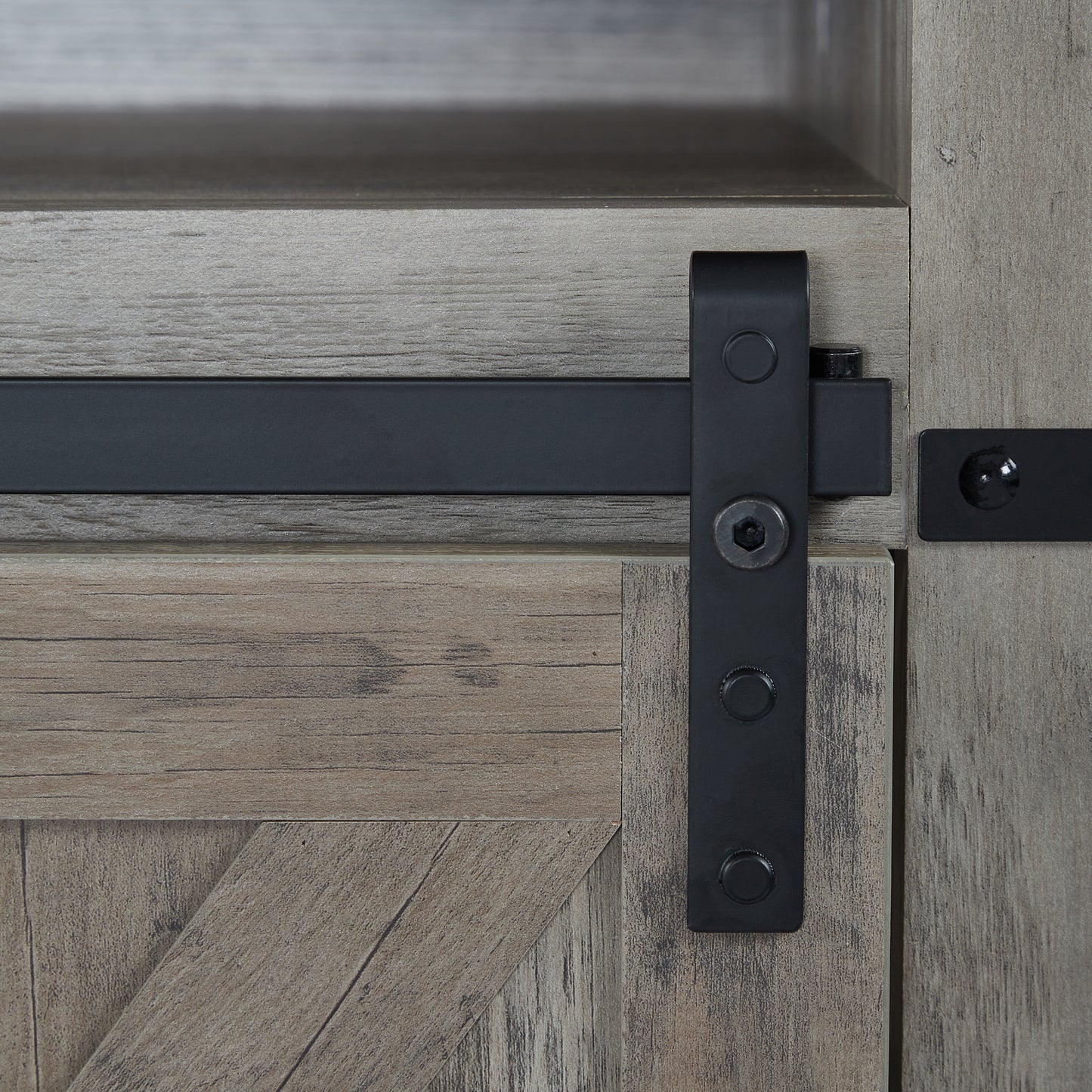 Closeup of weathered gray wood grain on a sliding barn door cabinet featuring black metal hardware