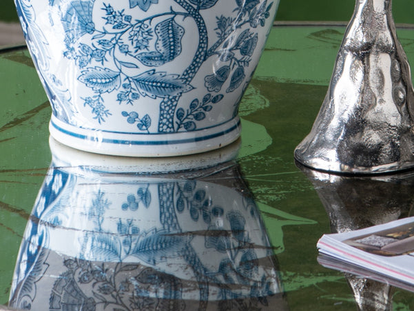 Blue and white porcelain vase with floral pattern reflecting on glass table