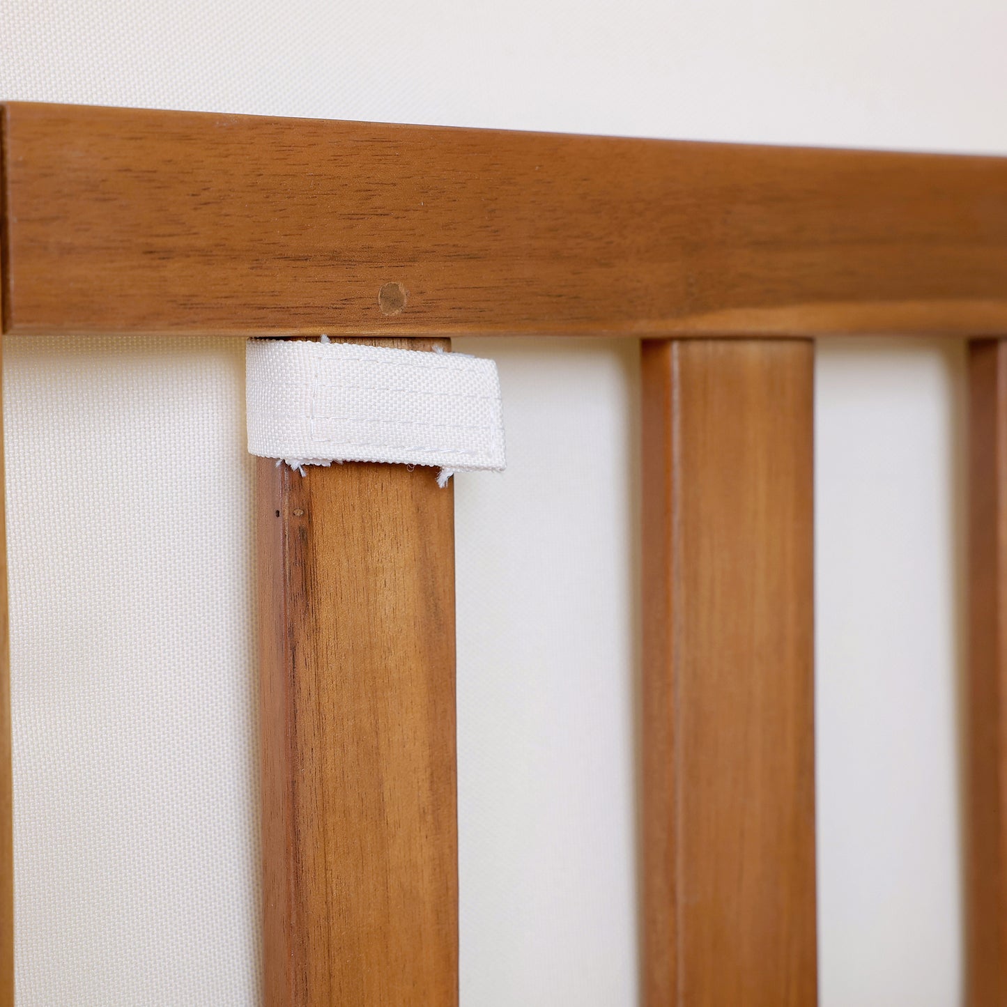 Natural wood chair detail with white fabric strap for cushion attachment