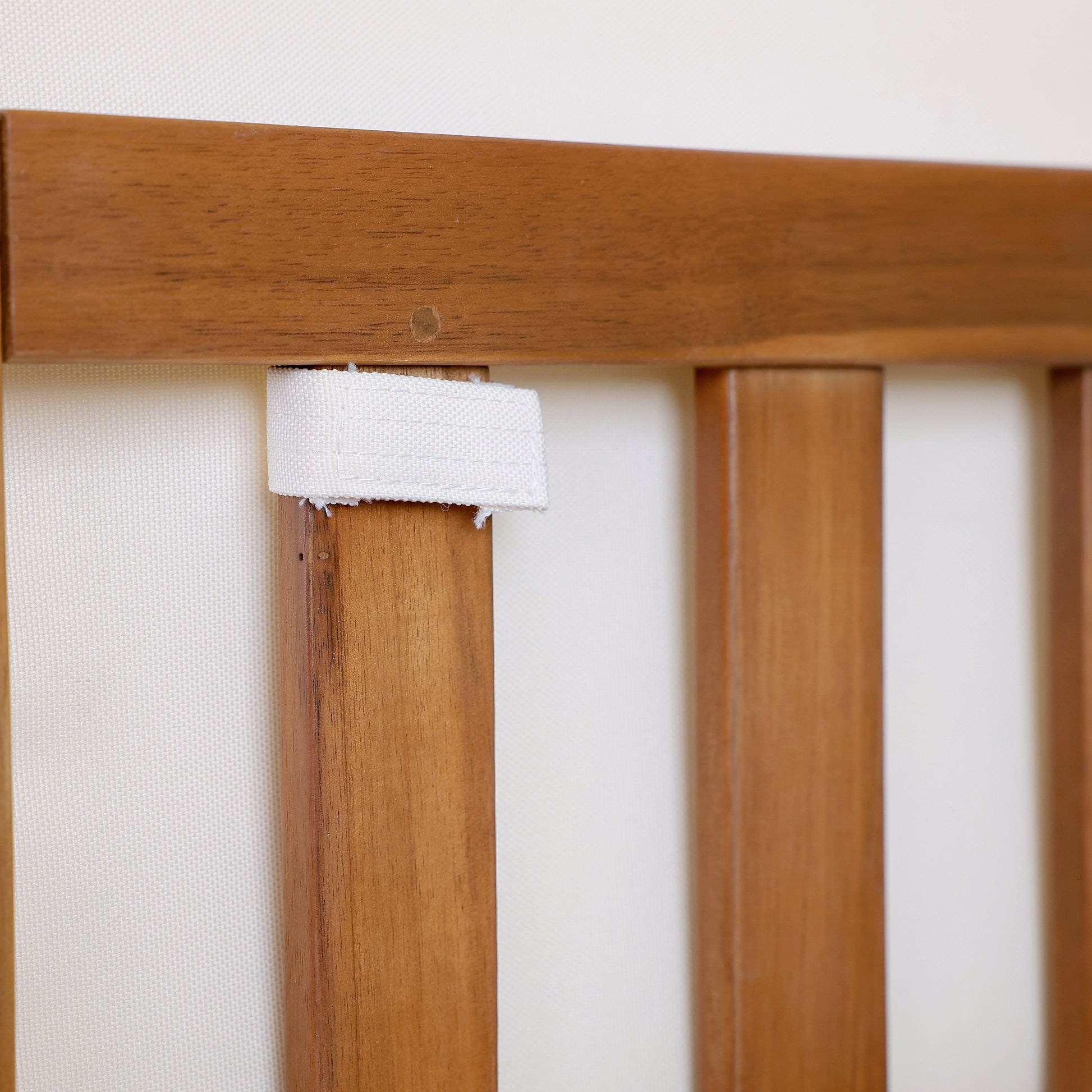 Natural wood chair detail with white fabric strap for cushion attachment