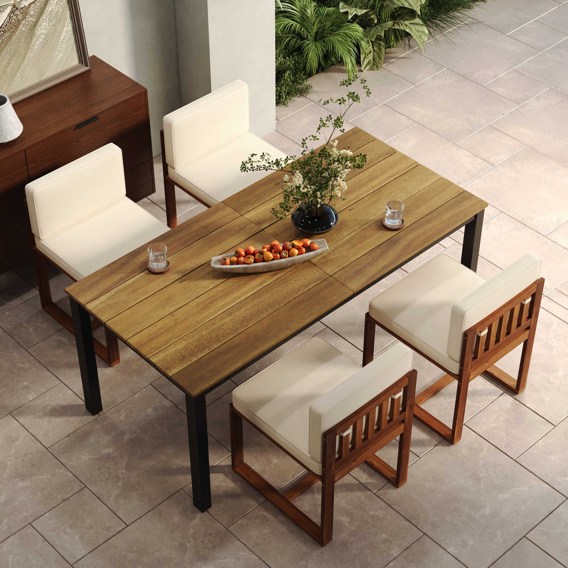 Wooden outdoor dining table with four cream cushioned chairs on a stone patio
