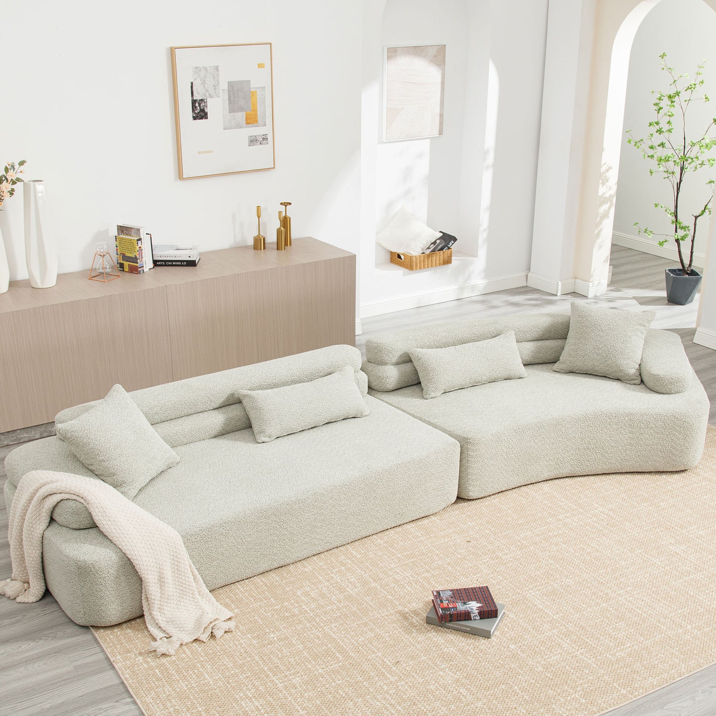 Boucle fabric modular sofa in cream with throw pillows and a cozy knit blanket draped over the armrest