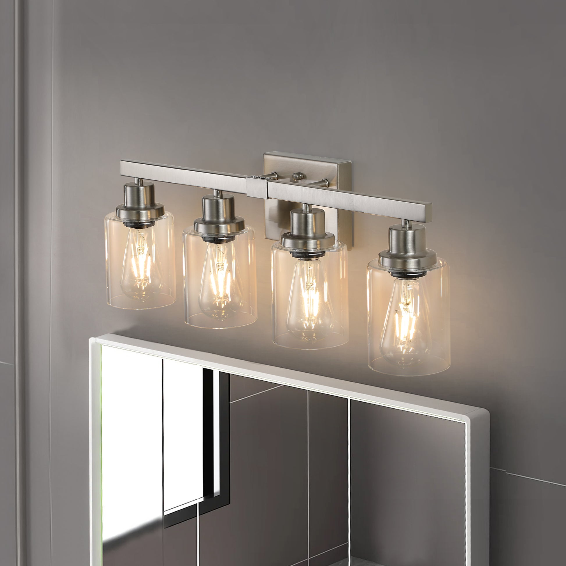 Modern brushed nickel vanity light with four clear glass shades and Edison bulbs
