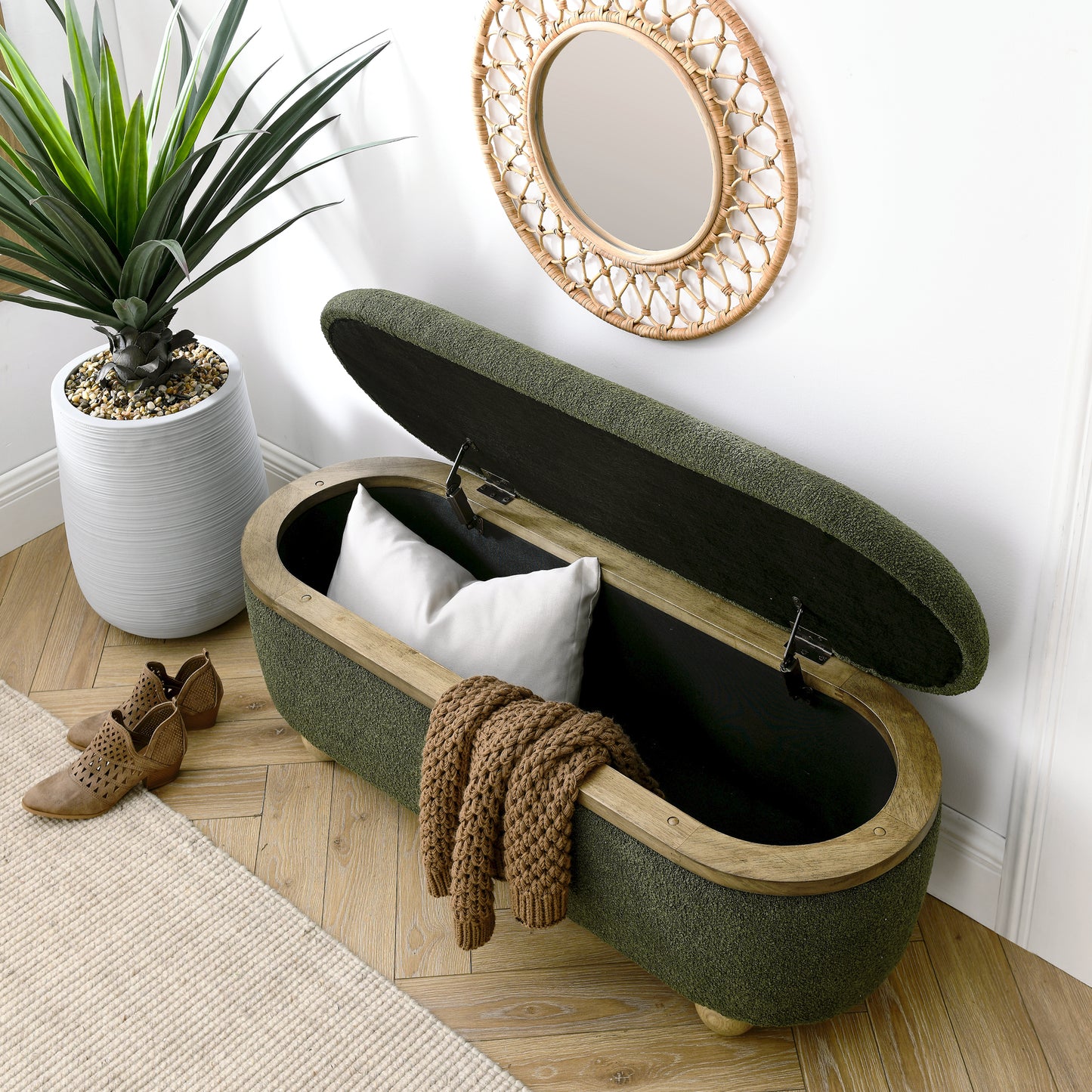 Green fabric ottoman bench with wooden trim open storage inside with pillow and blanket