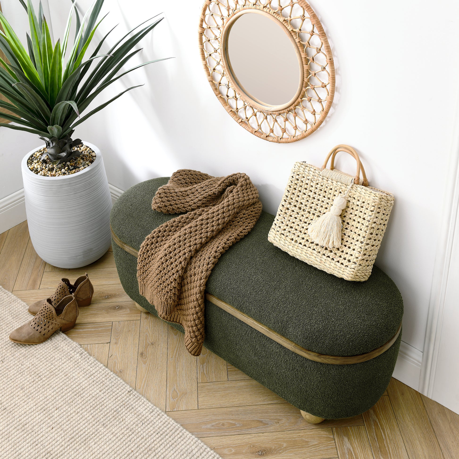 Dark green oval storage ottoman with wood trim and a knit throw