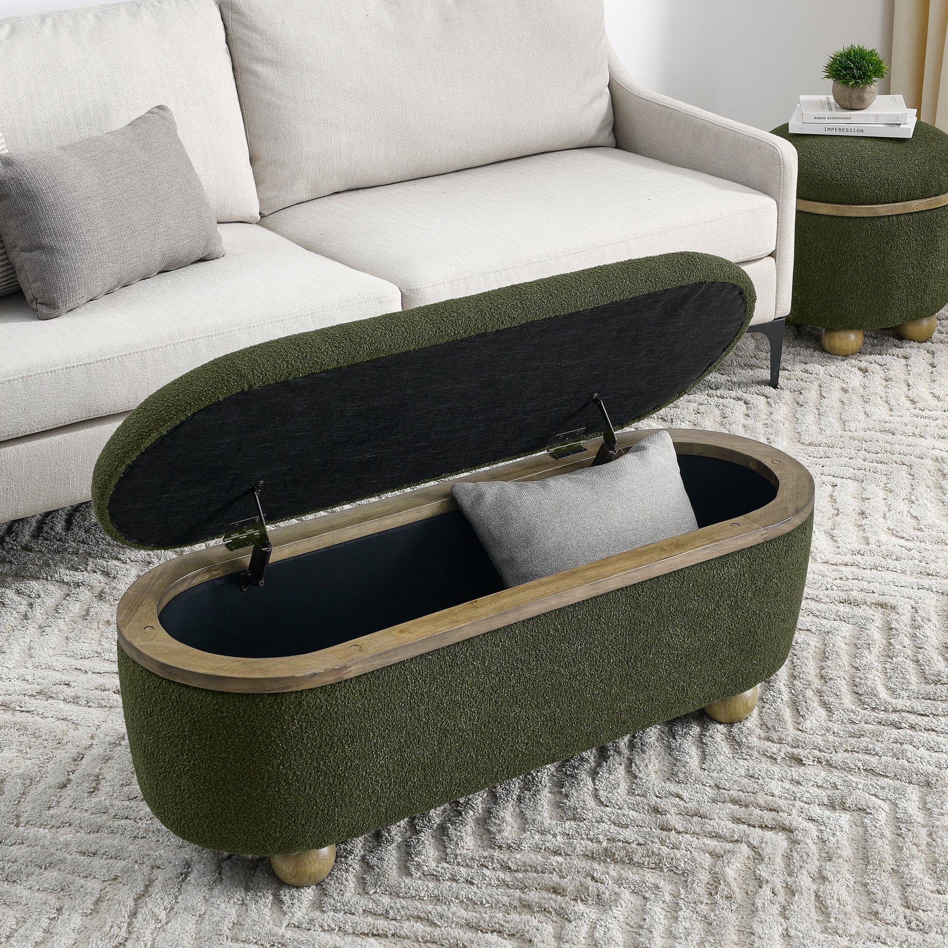 Olive green textured storage ottoman with wooden rim and ball feet open to reveal dark interior