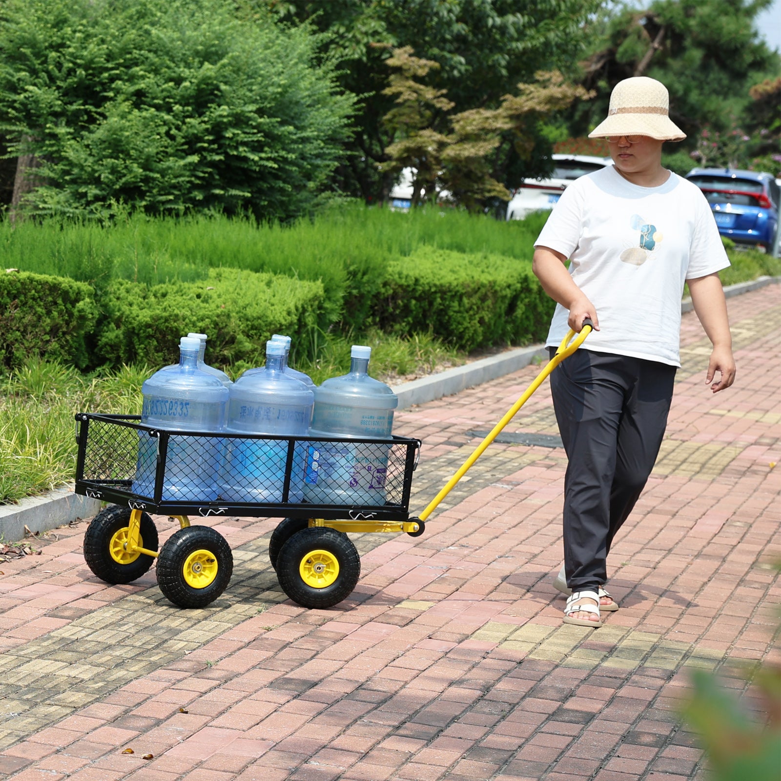 Yellow garden utility cart with four large water jugs pulled by a person