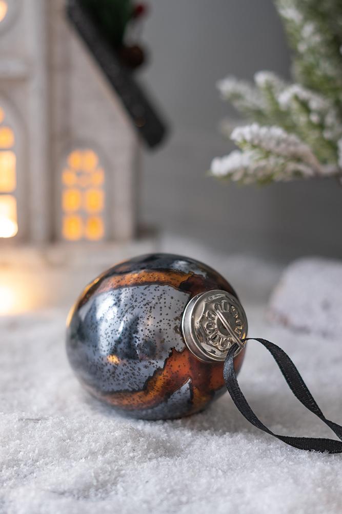 Antique silver and copper glass Christmas ornament with black ribbon on snow