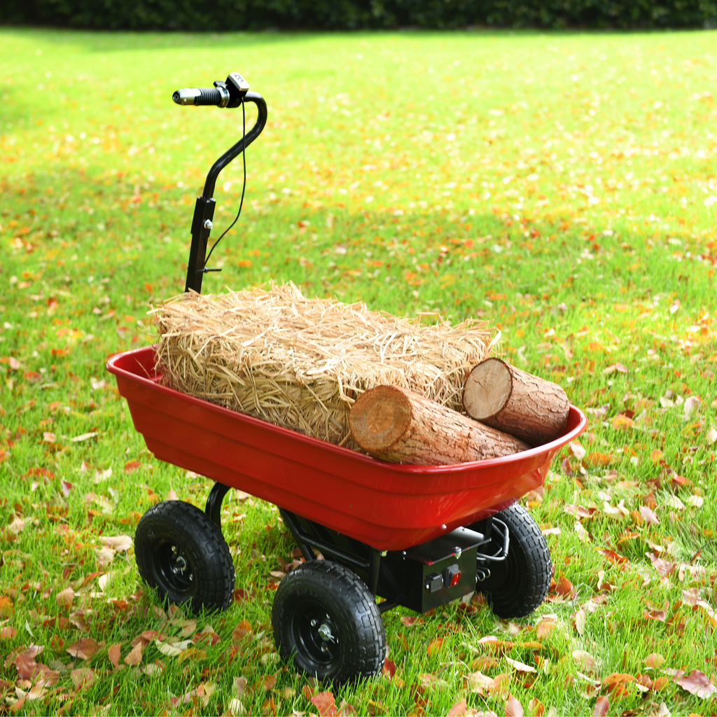 Red electric garden cart loaded with straw bale and logs on grassy lawn