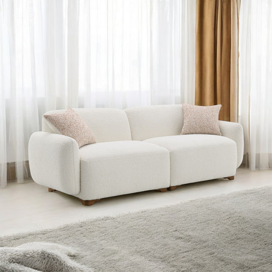 Plush white boucle fabric sectional sofa with wooden legs and textured throw pillows