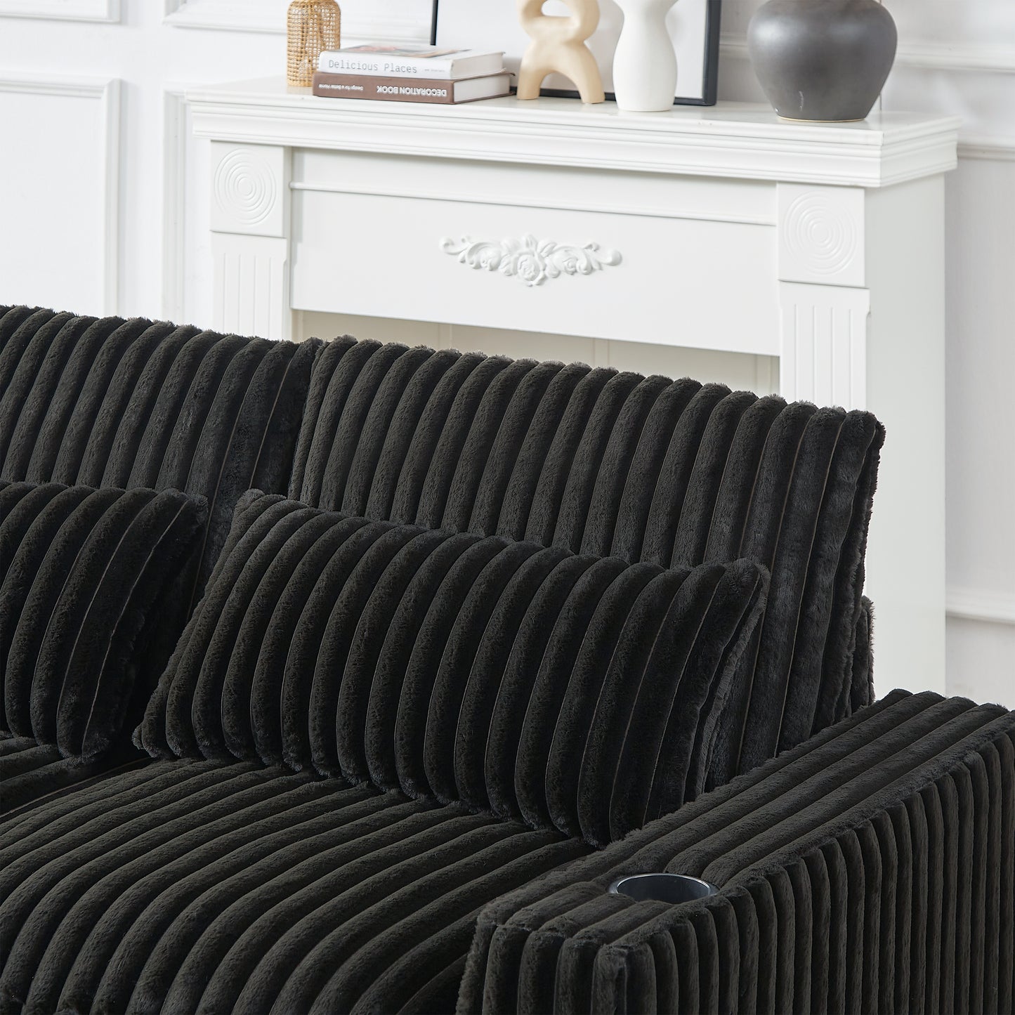 Black corduroy sofa with plush throw pillows and a builtin cup holder